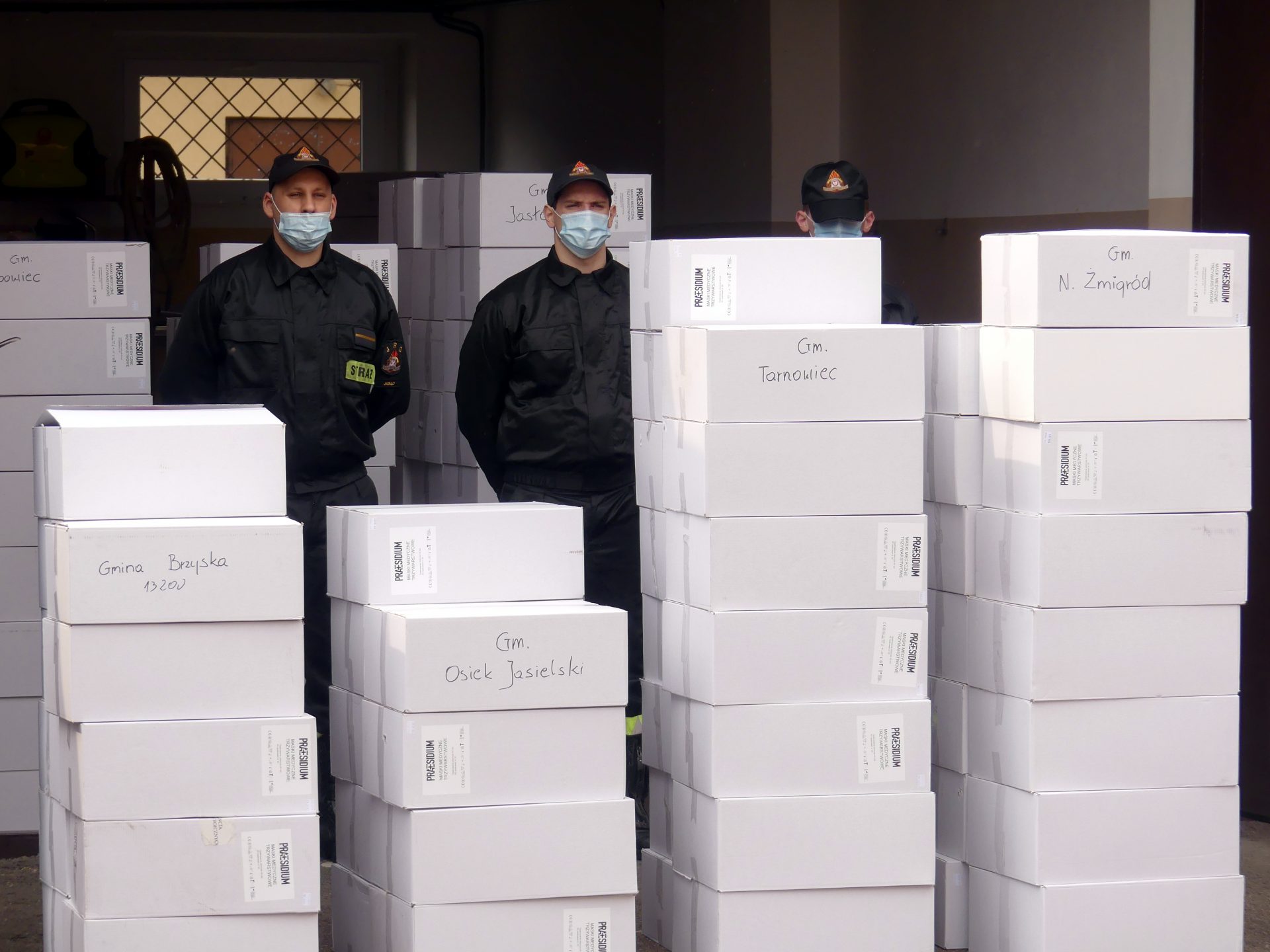 Strażacy komendy Powiatowej Państwowej Straży Pożarnej w Jaśle odbierają pudełka z maseczkami